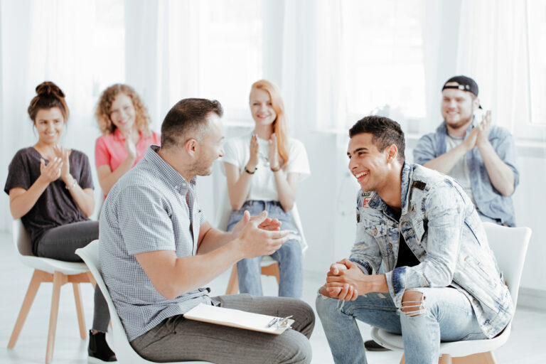The psychologist and his patients are laughing during a group session for addiction.