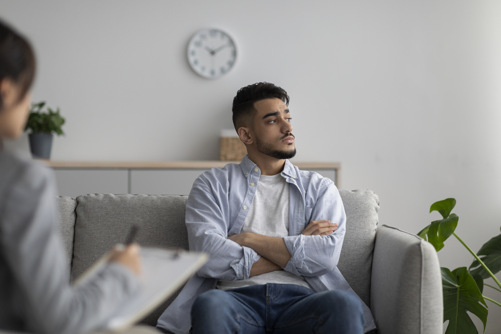 Psychotherapy concept. Depressed guy at counselor's office, seeking professional help with mental disorder. Professional psychologist having session with desperate male patient