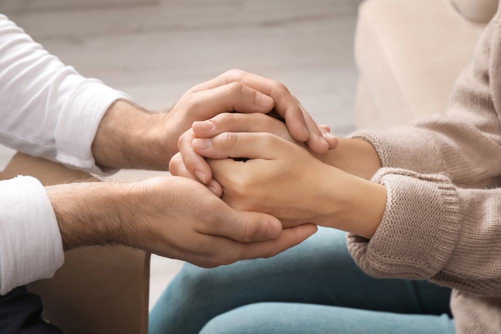 Man holding woman's hands indoors, closeup. Concept of rehab therapy support