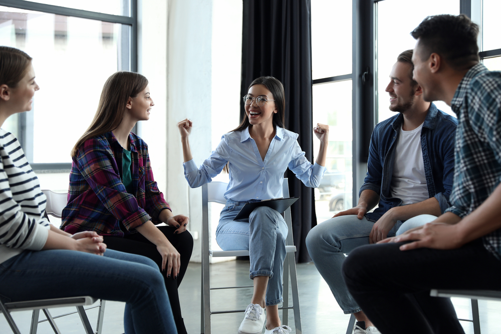 Psychotherapist working with patients in group rehab therapy session indoors